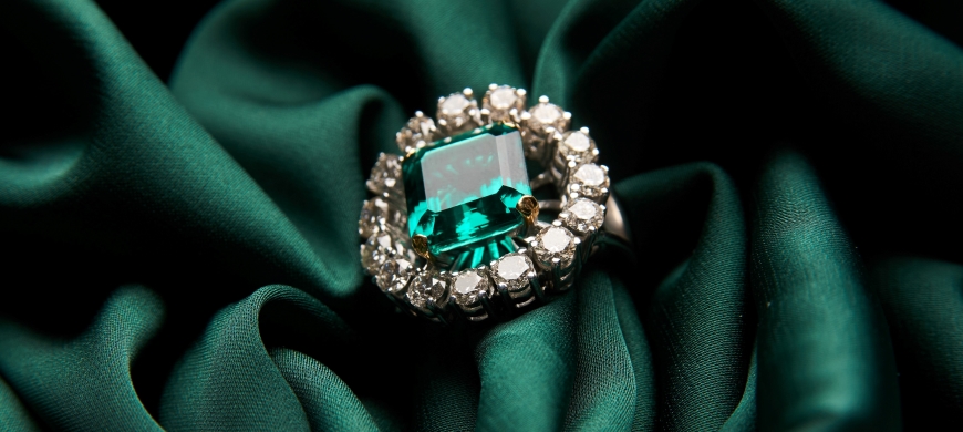 Emerald engagement ring on a green satin background