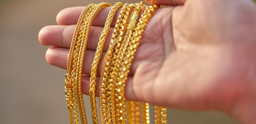 Different gold chains on a persons hand