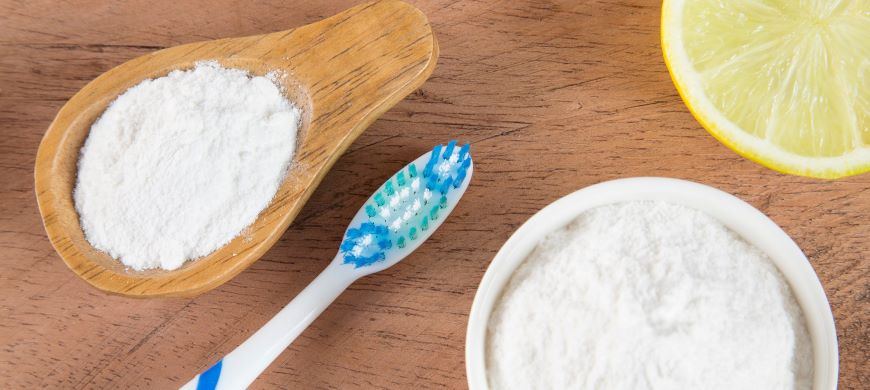 Picture of lemon, salt, baking powder, and a toothbrush on a wood background