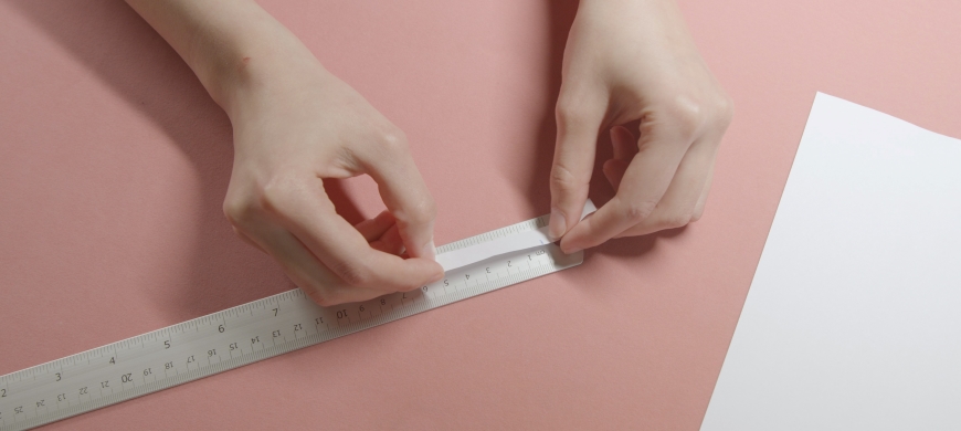 Person measuring paper ring against ruler
