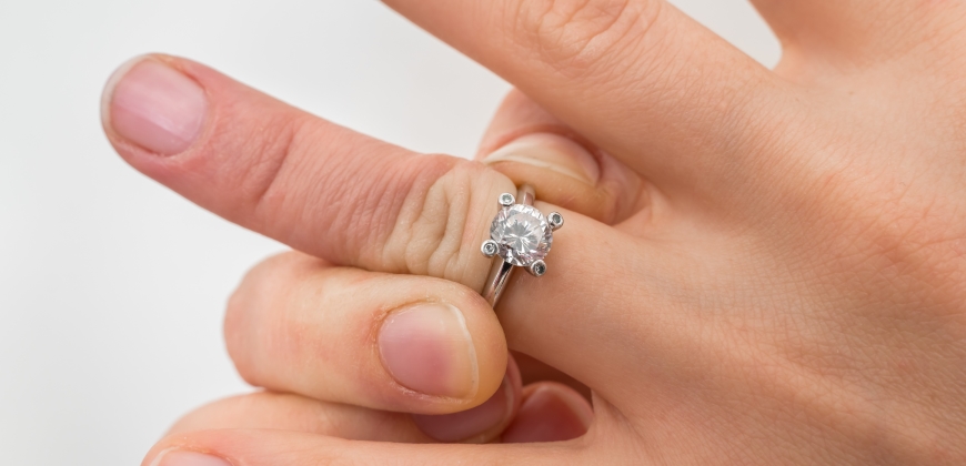 Person trying to pull off a ring stuck on their finger