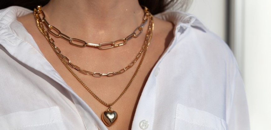 Person wearing three different gold necklaces layered
