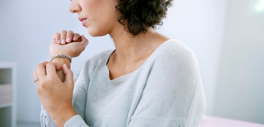 Picture of a person holding and scratching their wrist near their bracelet