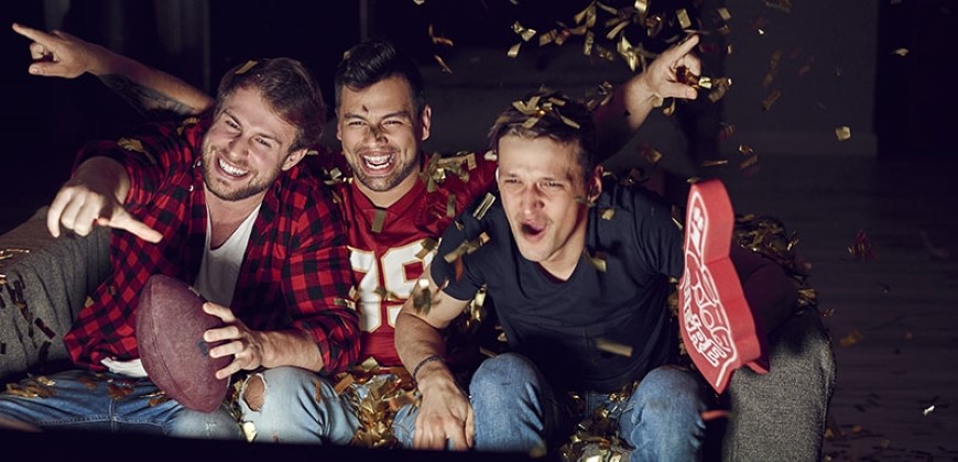 Three guys cheering at the tv