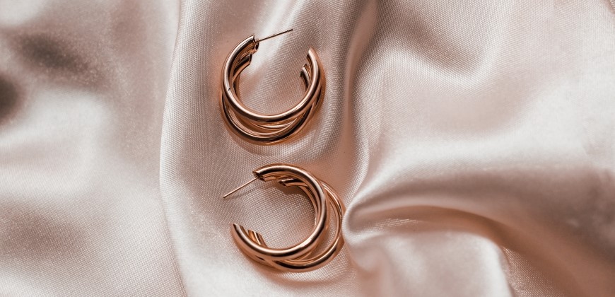 Two rose gold earrings on a silk rose gold background