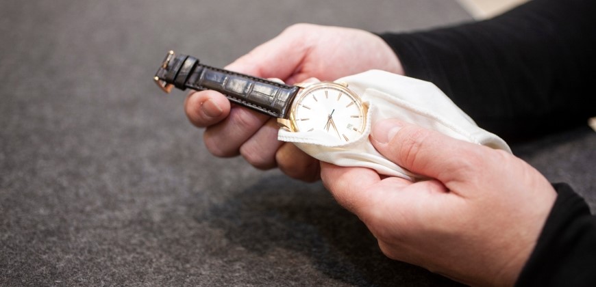Hands wiping a watch with a cloth