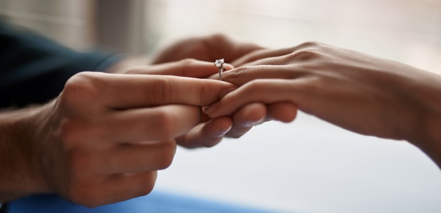 Man placing ring on woman's finger