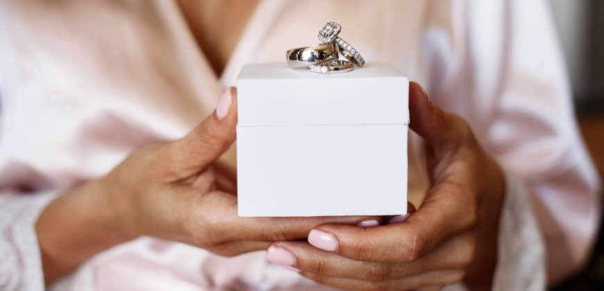 Bride holding a box with wedding rings on top of it