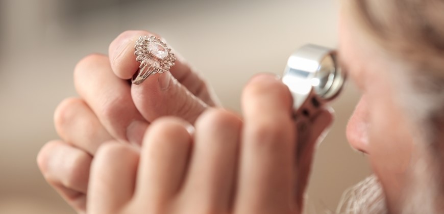 Jeweler looking at a diamond ring close up using a tool