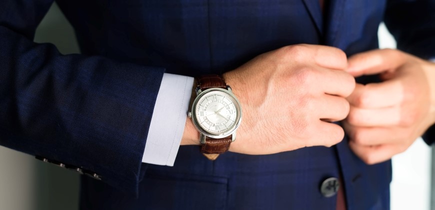 Close up of a person's wrist with a watch matching their suit