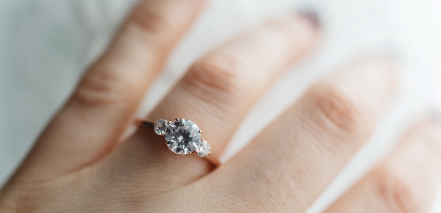 Close up of a three-stone diamond ring on a hand