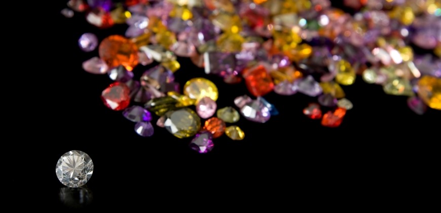 Picture of a colorless diamond with colored diamonds in the background