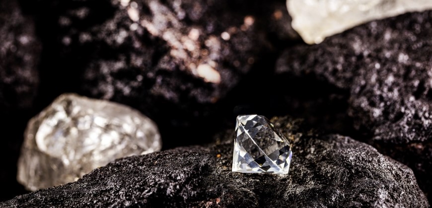 Picture of a cut diamond next to a raw natural diamond