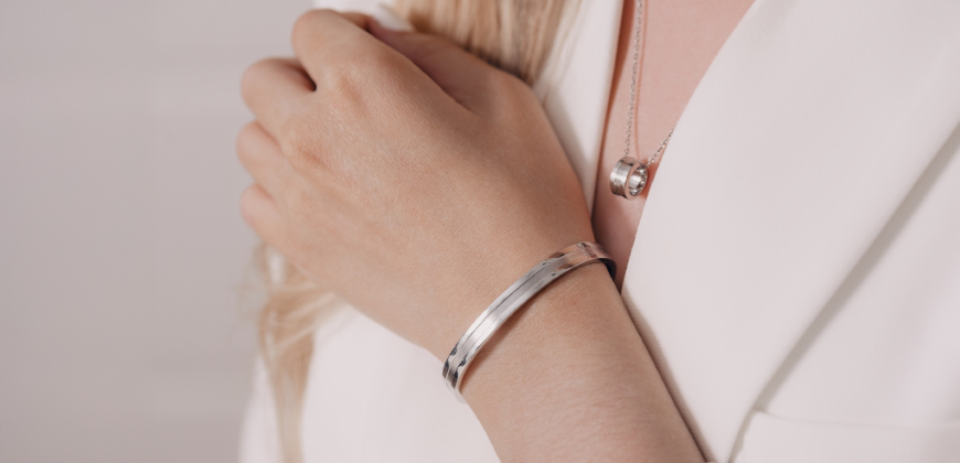Close up of someone wearing a silver bracelet and necklace