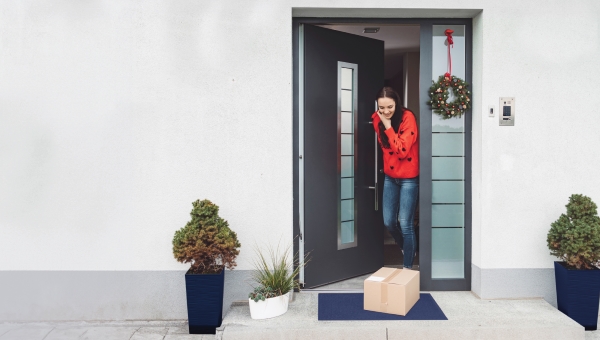 Woman opening her front door with packages on the porch