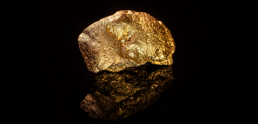 Large gold nugget reflecting on a black background