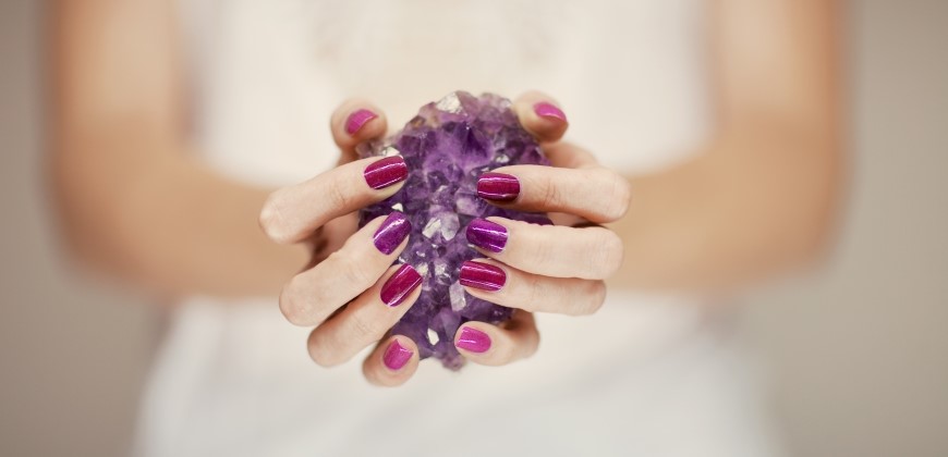 Hands holding an amethyst stone