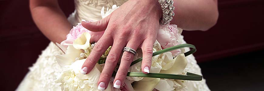 woman in floral lace wedding gown shows off antique ring while holding bouquet