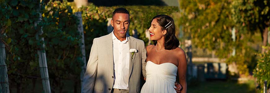 bride and groom walk down the path of a vineyard