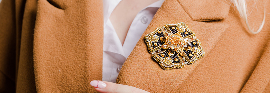 large black and gold diamond brooch on a burnt orange woman's suit coat