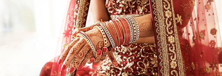 indian woman with henna on her hands slides on gold bracelet