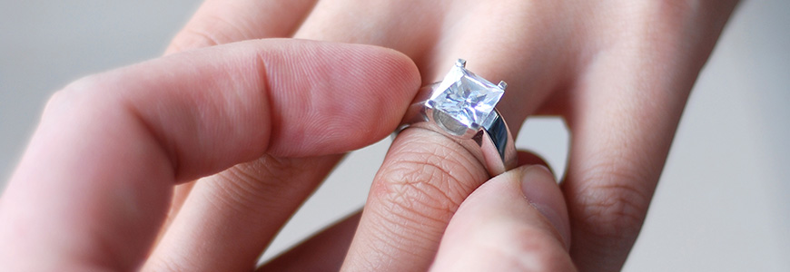 person places square French cut diamond onto female hand