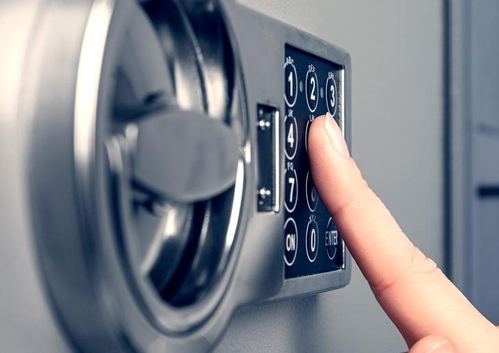 Hand typing on a keypad to open a safe