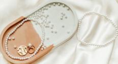 Pearls and pearl jewelry in a tray on a silky white background