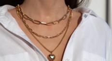 Person wearing three different gold necklaces layered