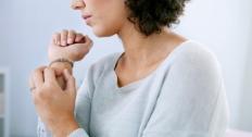 Person holding their wrist and itching wearing a bracelet