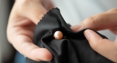 Black cloth wiping a pearl earring