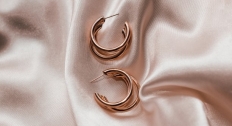 Two rose gold earrings on a silk rose gold background
