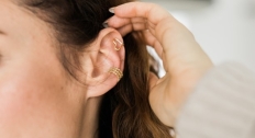 Womans hand behind her earring showing off her gold earrings