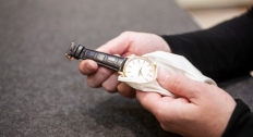 Hands wiping a watch with a cloth