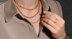Person wearing three gold necklaces and a gold ring