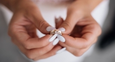Hands holding a gold ring and engagement ring together