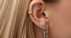 Close up of a person's ear with 7 different piercings and earrings