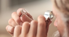 Jeweler looking at a diamond ring close up using a tool