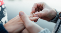 Close up of a man sliding an engagement ring on a woman's finger