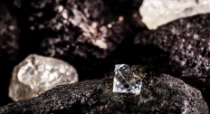 Picture of a cut diamond next to a raw natural diamond