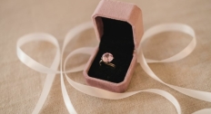 Pink diamond ring in a pink box with ribbon in the background