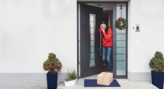 Woman opening her front door with packages on the porch