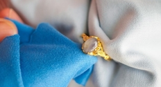 Hands holding a gold gemstone ring between two cloths