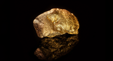 Large gold nugget reflecting on a black background