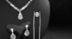 Diamond in a tweezer with a diamond necklace and earrings in the background