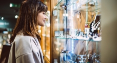 young brunette woman with bangs looks inside jewelry case full of necklaces and rings 
