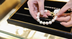 woman's ands pulling pearl necklace out of a cushioned jewelry box