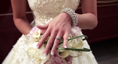 woman in floral lace wedding gown shows off antique ring while holding bouquet