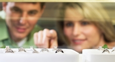 brunette man and blonde woman look inside jewelry case full of rings 