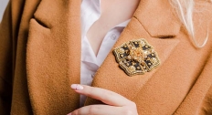 large black and gold diamond brooch on a burnt orange woman's suit coat